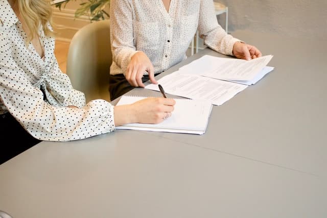 To kvinder med papirer der arbejder ved et bord